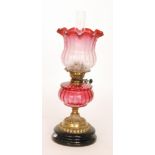 A Victorian style oil lamp and etched shade, ruby reservoir and brass basalt circular base,