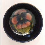 A small Moorcroft Pansy pattern footed bowl decorated with a central pink flower against a blue