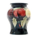 A small Moorcroft vase decorated in the Wisteria pattern decorated with a band of fruit against a