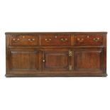 A George III oak and mahogany crossbanded three drawer dresser,