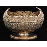 A hallmarked silver oval pedestal sugar basin with embossed foliate decoration below pierced shaped