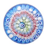 An early 20th Century John Walsh Walsh glass paperweight with rings of millefiori canes in blue,