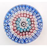 An early 20th Century John Walsh Walsh glass paperweight with rings of millefiori canes in blue,