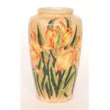 A Cobridge Pottery vase of barrel form decorated with flame orange iris flowers against a peach