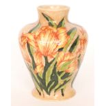 A Cobridge Pottery vase of shouldered form decorated with flame orange iris flowers against a peach