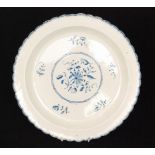 A 19th Century scalloped edge charger decorated in blue and white with a spray of flowers to the