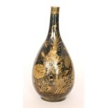 An early 20th Century Chinese bottle vase glazed in black with a gilt painted bird perched on a