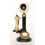 A candlestick telephone in black with brass fittings, later cord.