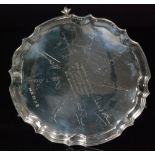 A hallmarked silver presentation salver of circular outline with pie crust border on three claw