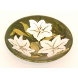 A Moorcroft bowl decorated in the Bermuda Lily pattern with white tubelined flowers against a green