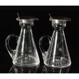 A pair of hallmarked and clear glass silver toddy water jugs,