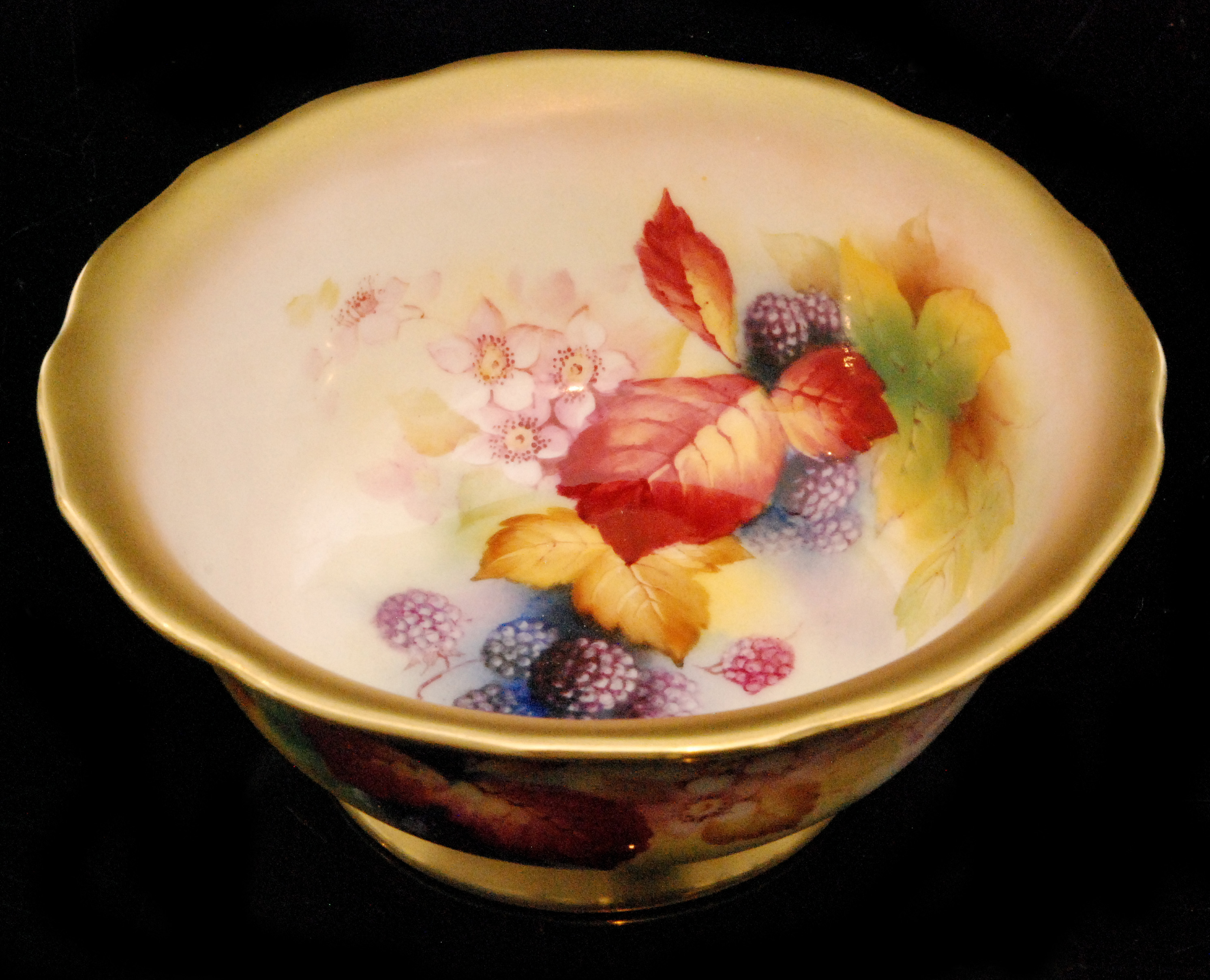 A Royal Worcester footed bowl decorated by Kitty Blake with hand painted autumnal fruits and