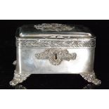 An early 20th Century continental white metal cushioned rectangular casket raised on four scroll