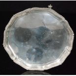 A hallmarked silver circular salver of plain from raised on three claw and ball feet and