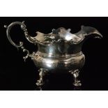 A hallmarked silver sauce boat raised on four stepped pad feet below reeded border and scroll