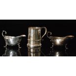 A pair of hallmarked silver sauce boats each raised on three pad feet and terminating in flying