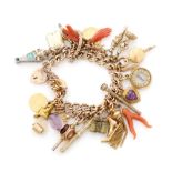 A hallmarked 9ct charm bracelet with multiple charms to include coral amulets, watch keys,