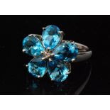 A modern 9ct white gold blue topaz and diamond cluster ring modelled as a flower head with five