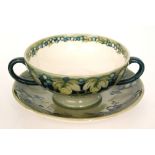 William Moorcroft - An early 20th Century twin handled soup cup and saucer decorated in the Celadon