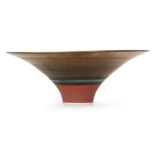Lucie Rie - A 1980s footed bowl with golden manganese glaze and rings of turquoise and charcoal