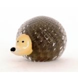 A contemporary studio glass figure of a hedgehog cased in clear crystal over tan with an applied