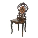 A late 19th Century carved Black Forrest hall chair the panel back and seat with marquetry inlay