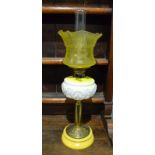 A late 19th Century brass oil lamp with yellow shade and reservoir on circular base,