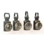 A black painted railway lamp with bulls eye lens and four similar hand lamps,