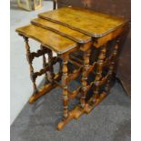 A nest of three walnut quarter veneered occasional tables with serpentine borders,