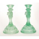 A pair of late 19th Century pressed glass candlesticks with a stepped domed base with foliate