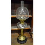 An Edwardian brass oil lamp with clear shade and reservoir on stepped black base,