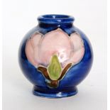 A miniature Moorcroft vase of footed spherical form decorated in the Magnolia pattern with pink