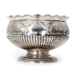 A hallmarked silver circular pedestal bowl with part fluted and foliate embossed decoration below