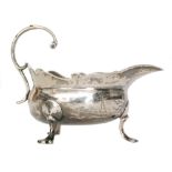 A George II hallmarked silver sauce boat of plain form with flying scroll handle,