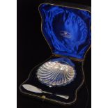 An Edwardian cased hallmarked silver shell shaped butter dish and conforming knife Birmingham 1903,