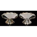 A pair of hallmarked silver pedestal nut dishes of plain form each with shaped reeded and shell