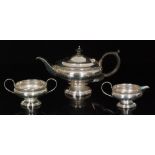 A hallmarked silver three piece pedestal tea set of plain circular from with egg and dart frieze to