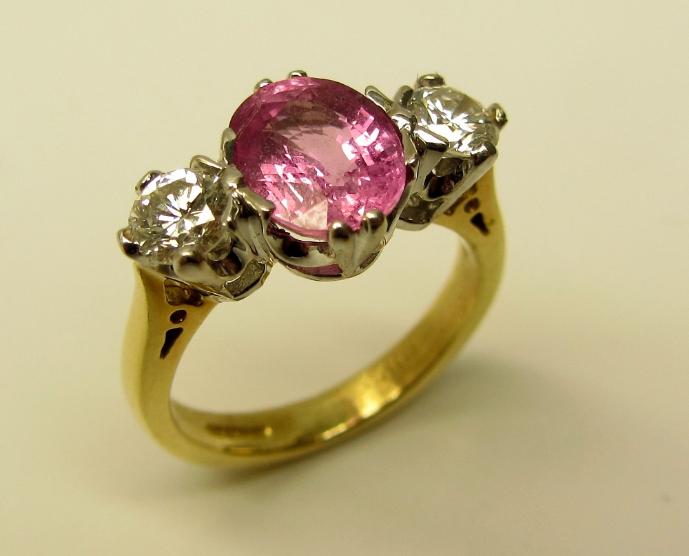 An attractive "Pink" sapphire Ring, with two diamonds, the central oval pink sapphire (1.