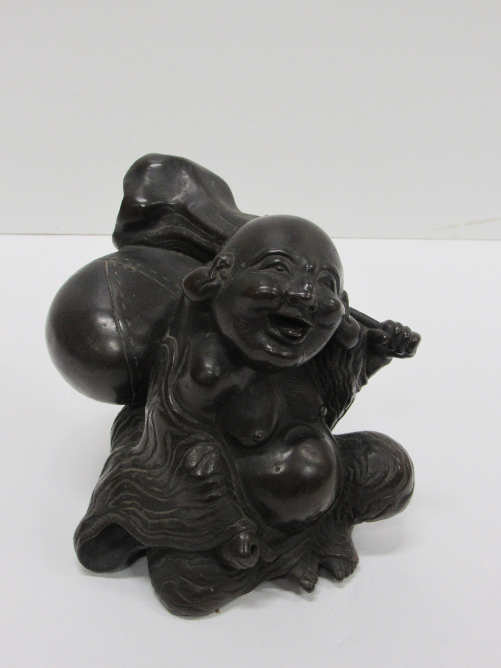 A heavy 19th Century Japanese bronze Figure of rotund Japanese Man, Hotri, seated with a backpack,