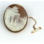 A very fine gold carved Cameo Brooch, of a woman standing outside a house, with safety chain.