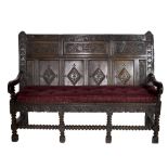 A good mid 18th Century profusely carved oak Settle, with panel back,