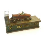 A GOOD 1920S CAST IORN AND PAINTED 'RACER' MONEY BOX, MOUNTED WITH A BUGATTI AND DRIVER, ON SPRING