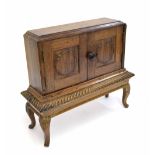 Miniature hardwood cabinet on stand, the top with fielded panelled doors on a base with a