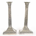Pair of George V silver reeded candlesticks, with Corinthian reeded columns and square stepped bases