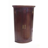 19th century mahogany bow fronted corner cabinet, the two panelled doors opening to reveal a shelved