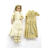 Small bisque-headed doll, in laced undergarments, blue spotted dress and brown bonnet, 12" high