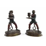 Pair of novelty printed cast metal candlesticks, modelled with standing monkeys wearing green and