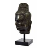 Eastern antique bronze head, with carved detail upon a square ebonised stand, 18" high