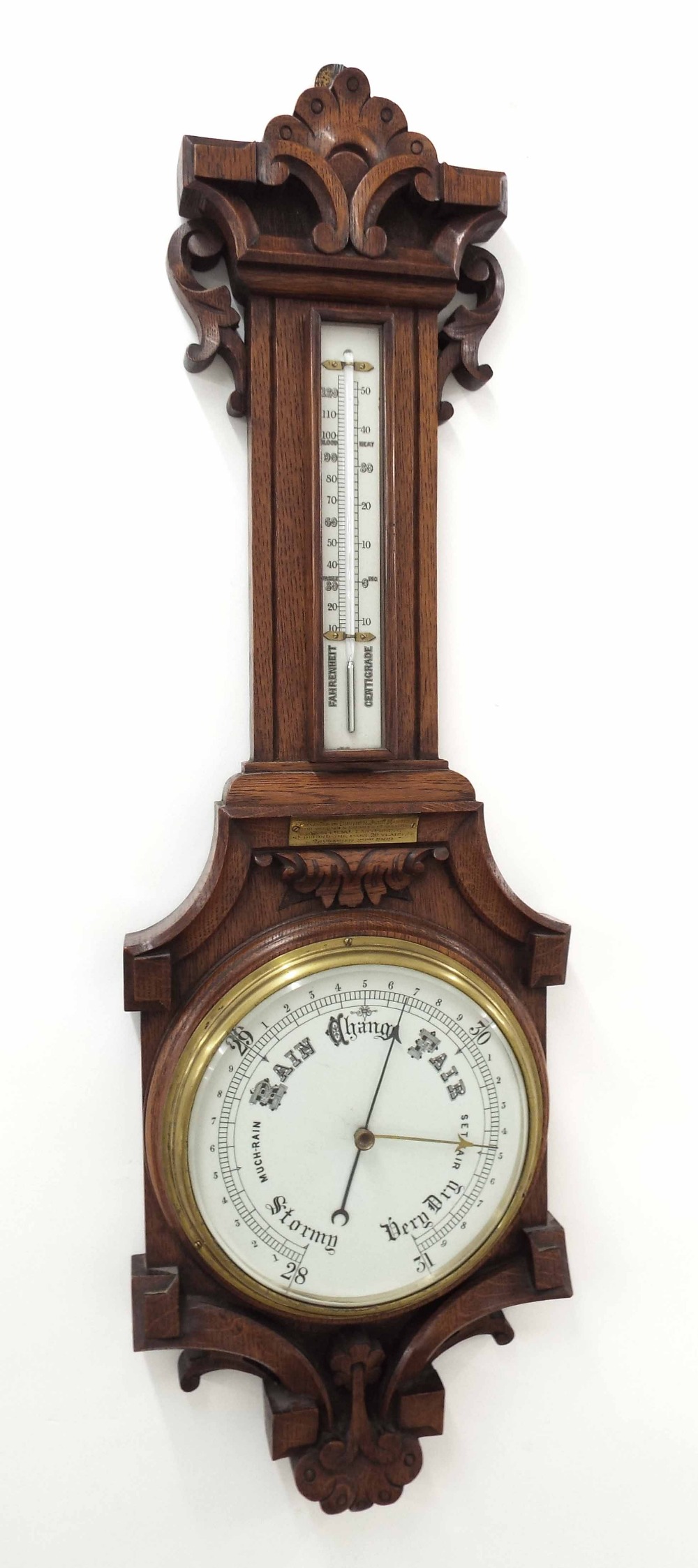 Oak barometer/thermometer, the 8" white dial within a good foliate carved shaped case *This