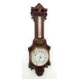 Oak barometer/thermometer, the 8" white dial within a good foliate carved shaped case *This